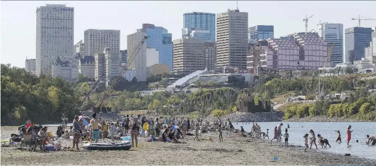  ?? CODIE MCLACHLAN ?? Sun seekers enjoy a hot day at the river valley’s new “accidental” beach downstream of the LRT bridge constructi­on site on Tuesday.