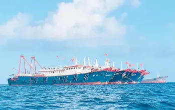  ?? PHILIPPINE COASTGUARD ?? Chinese vessels are anchored last month at Whitsun Reef, a boomerang-shaped feature that emerges above water only at low tide. At one point in March, more than 200 Chinese ships were reported anchored around the reef.