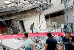  ?? AP ?? People inspect the rubble of a destroyed residentia­l building that was hit by an Israeli airstrike, in Gaza City.