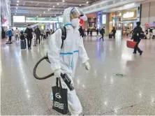  ?? ?? Personal sanitario equipado con traje protector contra el covid-19 fumiga la estación de trenes de Shanghai. (EFE)