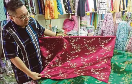  ?? BY GOH PEI PEI PIC ?? Chop Chin Nam owner Datuk Wee Hong Seng showing a fabric for cheongsam in Kuching recently.