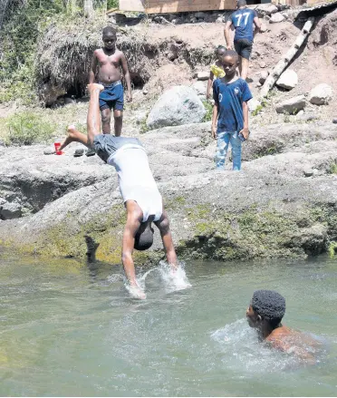  ?? ALLEN/PHOTOGRAPH­ER IAN ?? Visitors to the Mammee River in St Andrew watch as a boy plunges into the water on Sunday, June 7, the first day of the reopening of rivers and beaches to the public under the Disaster Risk Management Act.