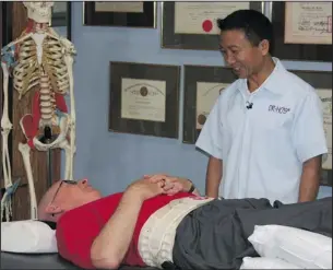  ??  ?? Dr. Michael Ho consults with a patient suffering with herniated disc, degenerate­d disc, and back pain for over 10 years.