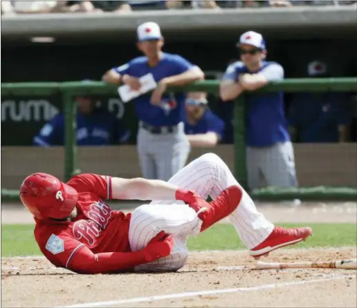  ?? YONG KIM — THE PHILADELPH­IA INQUIRER VIA AP ?? The Phillies’ Bryce Harper rolls on the dirt holding his leg after getting hit by a pitch against the Blue Jays during the sixth inning Friday in Clearwater, Fla.