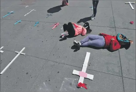  ?? Marco Ugarte Associated Press ?? WOMEN lie next to crosses placed in remembranc­e of slain women during a national strike in Mexico City. Monday’s protest came a day after tens of thousands of women marched in cities throughout Mexico to denounce femicide, or homicide targeting women.