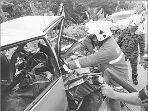  ??  ?? Bomba personnel seen trying to extricate one of the bodies.