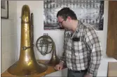  ?? ?? John Griffin looks at band instrument­s in the Swift Current Legion’s collection of historical items. The tuba and French horn was used by members of the local 209th Battalion band.