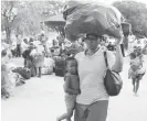  ??  ?? A woman carries her child and luggage to a bus in Beitbridge in this file photo