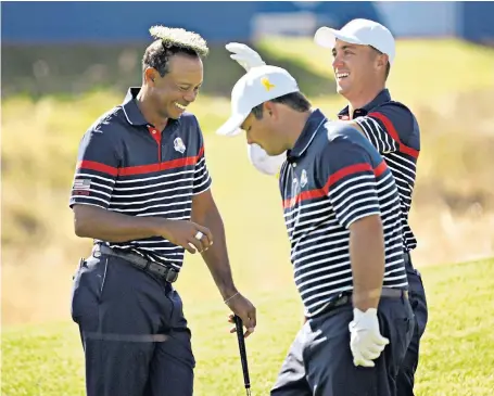  ??  ?? Tufts on top US golfer Justin Thomas has a laugh at team-mate Tiger Woods’ expense, placing a clump of grass on the 14-time major winner’s thinning head of hair. The pair were practising on a course near Paris for the Ryder Cup, which starts today.