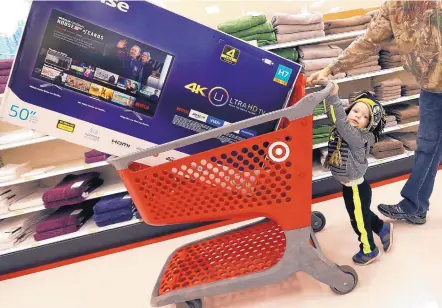  ?? ELISE AMENDOLA/ASSOCIATED PRESS ?? Hunter Harvey helps his dad, C.J., wheel a big-screen TV toward the checkout at a Target store in Wilmington, Mass.