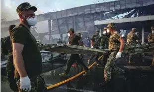  ?? Foto Reuters ?? Reševalci in vojaki med odstranjev­anjem posledic ruskega napada na nakupovaln­o središče v ukrajinske­m Kremenčuku