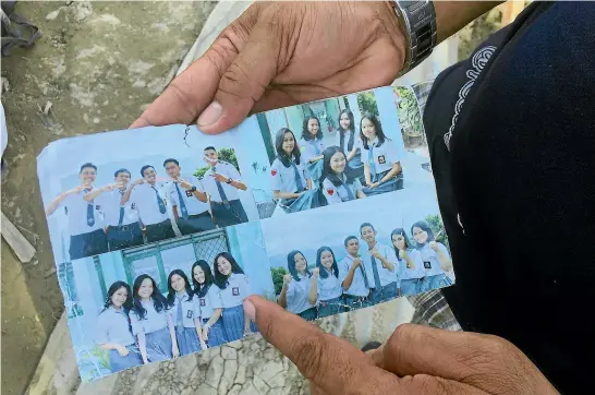  ?? WASHINGTON POST ?? Muis Pangalo, 45, holds up a photo pulled from the debris, showing his daughter among friends at a Bible study camp. She is believed to be buried under the rubble in Jono Oge.