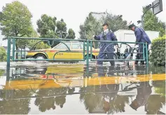  ??  ?? Policemen remove leaves from a drain on a flooded road in Tokyo. — AFP photo