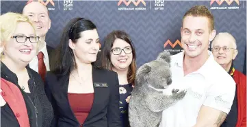  ??  ?? Johnson (third left) and Belov (left) attend a press conference as Chad Staples (second right) from Featherdal­e Wildlife Sanctuary holds a four-year-old koala named Archer in Sydney. — AFP photo