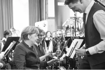  ??  ?? Merkel speaks with musicians of a band at an election rally in Brilon, western Germany. — AFP photo