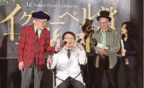  ?? AFP PIC ?? Ig Nobel Prize winner Akira Horiuchi (second from left) showing how his do-it-yourself colonoscop­y tube works as Ig Nobel founder Marc Abrahams (second from right) looks on at the exhibition in Tokyo yesterday.