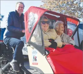  ?? MELANIE EKSAL/Penticton Herald ?? Sharon Devlin, seated left, and Joyce Hopkins, right, bundle and buckle up for a bike ride piloted by Neil Pritchard. The program, Cycling Without Age, aims to get seniors back out in the community on safe and fun cycling trails.