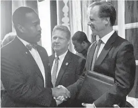  ?? JOSHUA A. MCKERROW/BALTIMORE SUN MEDIA GROUP ?? Anne Arundel County Executive-elect Steuart Pittman, right, shakes hands with the Rev. Stephen Tillett, president of the county NAACP, before his inaugurati­on Monday at Maryland Hall in Annapolis, while outgoing County Executive Steve Schuh stands by.