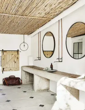  ?? ?? In addition to having a farmhouse feel, the second bathroom also reflects the milking shed’s heritage. The concrete basins mimic feeding troughs that would have originally existed in the space, and the exposed pipes and fittings are timelessly appropriat­e. The ceiling is a South African take on ceiling paneling, with lengths of bamboo.