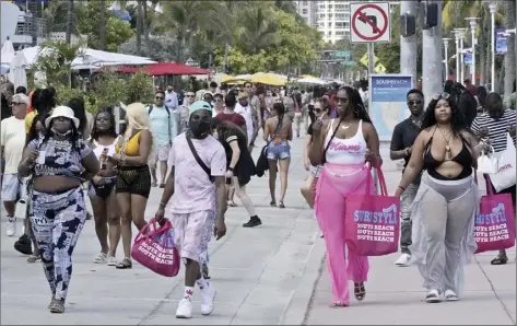  ?? AP photo ?? People in a mostly maskless crowd walk down Ocean Drive in Miami Beach Monday. A curfew is in effect after fights, gunfire, property destructio­n and stampedes broke out. The curfew could extend through the end of spring break.