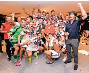  ?? FOTO: LARS BARON/GETTY IMAGES ?? Joachim Löw feiert in der Kabine des Maracana-Stadions von Rio de Janeiro mit seinen Spielern, Bundespräs­ident Joachim Gauck und Bundeskanz­lerin Angela Merkel den Gewinn des WM-Titels 2014.