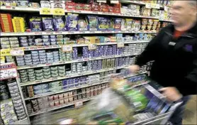  ??  ?? A shopper walks by cans of tuna fish on display in a grocery store in Des Plaines, Illinois. Tuna giant Bumble Bee Foods has pleaded guilty in a price-fixing conspiracy.