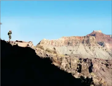  ?? DINA MISHEV/THE WASHINGTON POST ?? Two-thirds of the way down the South Kaibab Trail, a hiker stops to take a photograph of the Colorado River. Between the canyon’s South Rim and the Colorado River, the trail passes through 30-some layers of rock, which cover 1.8 billion years of...