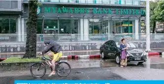  ??  ?? YANGON: A man on bicycle rides past Myawaddy Bank yesterday.