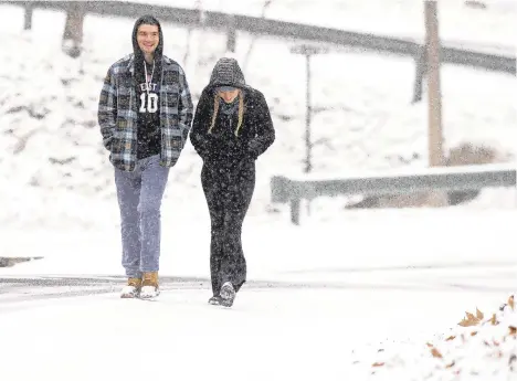  ??  ?? RIGHT: Lehigh University students Cormac O’Day, of Fairfield, Connecticu­t, and his friend, Caroline Vena, of Morgantown, NewJersey, take time out from studying and take a walk Wednesday along Upper Sayre Park Road in Bethlehem as the area receives its first snowfall of the season.