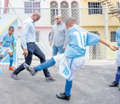  ?? CONTRIBUTE­D PHOTOS ?? Members of Catherine Hall Primary & Infant School’s football team christened the newly-refurbishe­d Catherine Hall multi-purpose court following the ribbon cutting, by challengin­g Robert Rodney, terminal manager at New Fortress Energy in Montego Bay and Councillor Dwight Crawford, to a game of scrimmage.