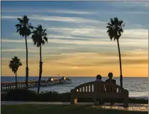  ?? LEONARD ORTIZ — STAFF PHOTOGRAPH­ER ?? Two women look out over San Clemente Pier at sunset from a bench at Parque del Mar in San Clemente in 2023.