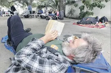  ?? Irfan Khan Los Angeles Times ?? MIKE ALBRIGHT, 58, reads a book at a Pomona shelter. The county homeless population surged in 2016.