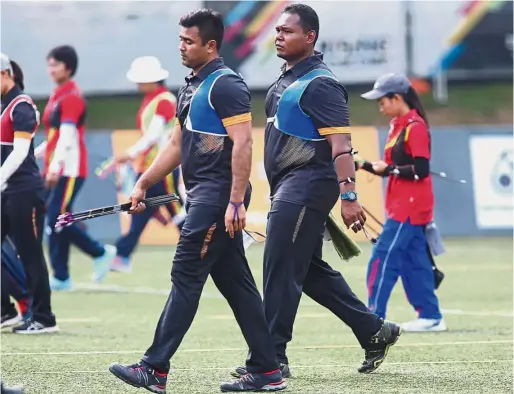  ??  ?? Shoulderin­g the burden: Malaysian men’s recurve archers Haziq Kamaruddin (right) and Khairul Anuar Mohamed during their practice session at the National Archery Range in KL Sports City yesterday.