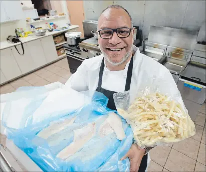 ?? PETER LEE WATERLOO REGION RECORD ?? Chef Derek Hines holds an armload of fish and chips inside the kitchen at the Waterloo Knights of Columbus hall on Dearborn Place.