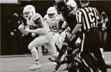  ?? Sue Ogrocki / Associated Press ?? Texas linebacker Joseph Ossai, left, recovers an Oklahoma State fumble in the second half of Saturday’s overtime road victory. Ossai, a former Oak Ridge star, also had 12 tackles, six for loss, and three sacks.