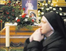  ?? Beata Zawrze ?? The Associated Press A nun prays beside the casket and photo of 110-year-old Roman Catholic Sister Cecylia Roszak, believed to be the world’s oldest nun, during funeral ceremonies Thursday at Church of Our Lady of the Snows the Dominican in Krakow, Poland.