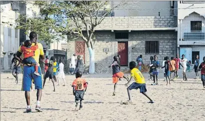  ?? LA VANGUARDIA ?? Lima, con un niño a su espalda, dirige un entrenamie­nto en el campo de la escuela de fútbol