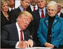  ?? ALEX WONG / GETTY IMAGES ?? President Donald Trump signs his executive order on health insurance as Sen. Rand Paul (above left), R-Ky., Vice President Mike Pence and
Rep. Virginia Foxx, R.-N.C., look on in the Roosevelt Room of the White House on Thursday.