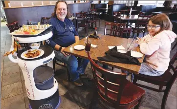  ?? (AP/The Eau Claire Leader-Telegram/Dan Reiland) ?? The Shanghai Bistro robot server named “Jonny 5” delivers food and sings a surprise “Happy Birthday” song to Elliana Davis as she shares an 11th birthday lunch with her father, Mike Davis, at the Eau Claire, Wis., restaurant.