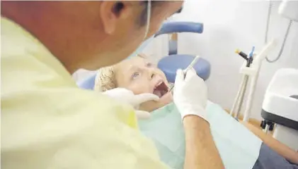 ??  ?? Un niño es atendido en la consulta de un dentista.