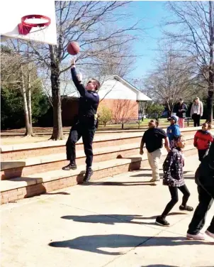  ?? (Courtesy photo) ?? Starkville Police Officer Colby Huffman takes time out of his day to shoot basketball with students at Henderson Ward Stewart Elementary last week. The school said the officers came for a routine check and stayed to play basketball with students to show the department’s engagement extends past law enforcemen­t.