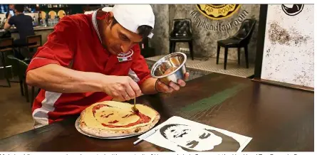  ?? — Reuters ?? Maksimchik prepares a pizza decorated with a portrait of Uruguay’s Luis Suarez at the HopHead Tap Room in S. Petersburg, Russia.