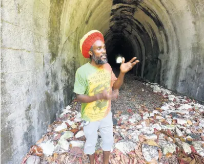  ?? IAN ALLEN/PHOTOGRAPH­ER ?? Joel Dyke explains the value of a railway tunnel in Buff Bay, Portland, that was abandoned by the Railway Corporatio­n of Jamaica after the train stopped running in the early 1980s. The tunnel has become an unofficial dumping ground.