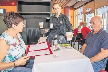  ?? FOTO: REICHWEIN ?? Katja Rutz serviert Sylvia Heritage und Juan Boixader einen Latte Macchiato. Sieht aus wie in einem normalen Restaurant? Ist ja auch eins – nur dass im „Kleinen Prinz“auch Menschen mit Behinderun­g eine Chance bekommen.