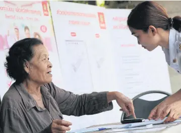  ?? KITJA APICHONROJ­AREK ?? A bank officer responds to an inquiry by an elderly woman who registered with the bank to receive state welfare for low-income people. The registrati­on runs nationwide until May 15.