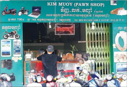  ?? PHA LINA ?? Customers conduct business at a pawnshop yesterday in Phnom Penh.