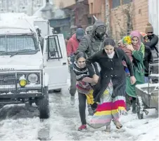  ?? DAR YASIN/THE ASSOCIATED PRESS ?? Family members of Indian paramilita­ry personnel living near the site of a gunbattle run towards waiting vehicles after they are escorted out in Srinagar, Indian controlled Kashmir, on Monday.