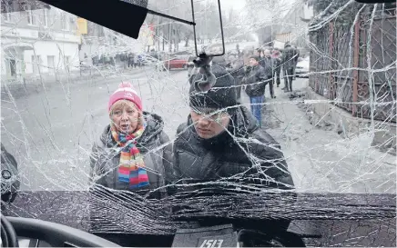  ?? Photo: REUTERS ?? Devastatin­g: Witnesses look through the front windshield of a damaged trolleybus in Donetsk. At least 13 civilians were killed yesterday when a shell or a mortar hit a trolleybus stop in the rebel-controlled city, in eastern Ukraine.