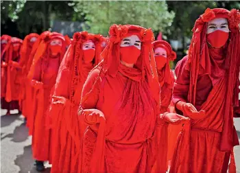  ?? — AFP ?? Activists from the climate change protest group Extinction Rebellion, dressed in red robes and known as the Red Brigade, demonstrat­e in Falmouth, Cornwall during the G7 summit on Saturday.