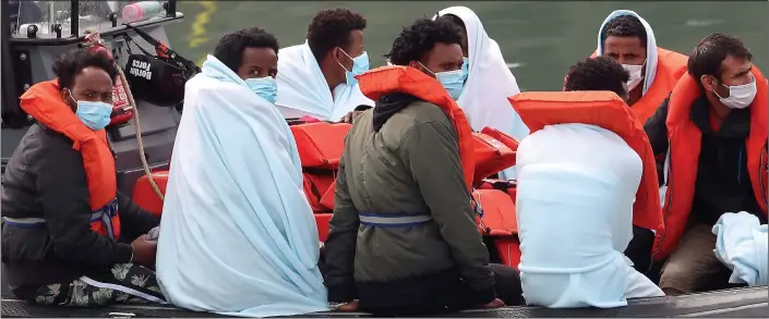  ??  ?? DESPERATE: An all-male group of migrants intercepte­d yesterday, while another boat carried just women, below left. Below right: A lifeboat tows a dinghy, without an outboard motor so it couldn’t be sent back